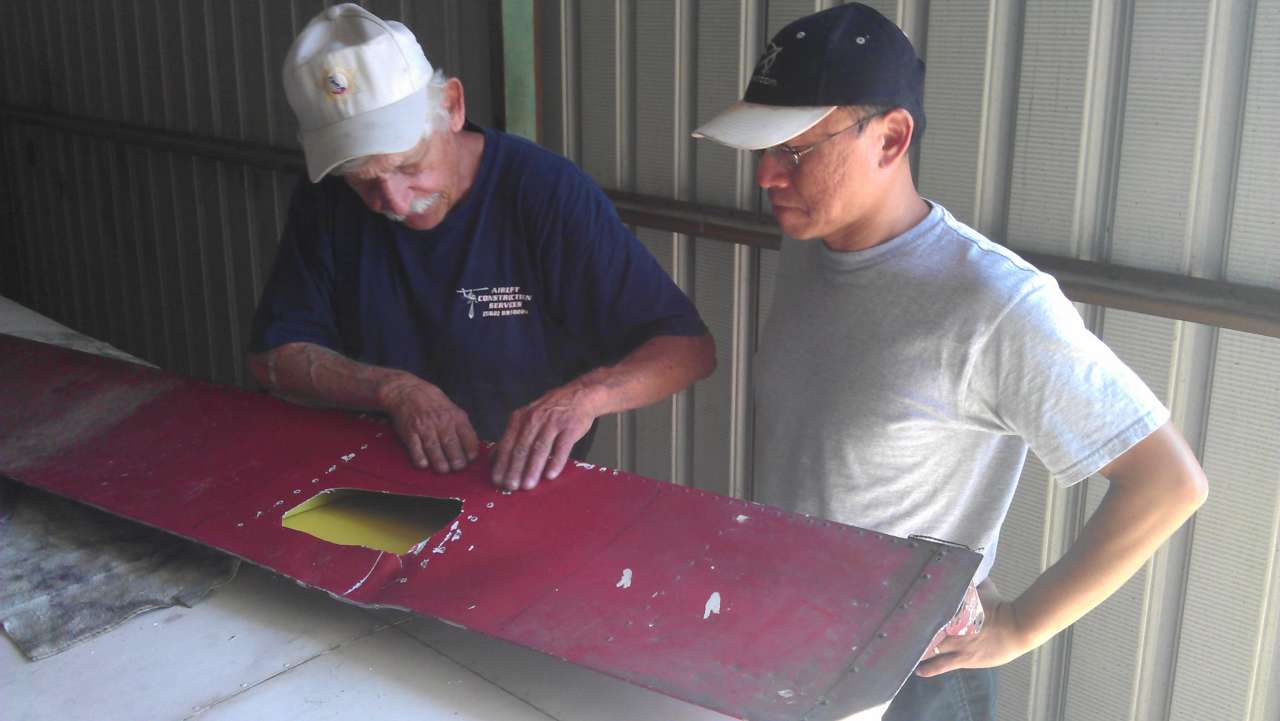 Sheet metal man Chuck showing Robin his plan to repair right flap